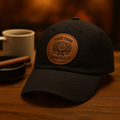 Black unstructured dad hat with a round leather patch engraved with the Pirate Cigar kraken crest
