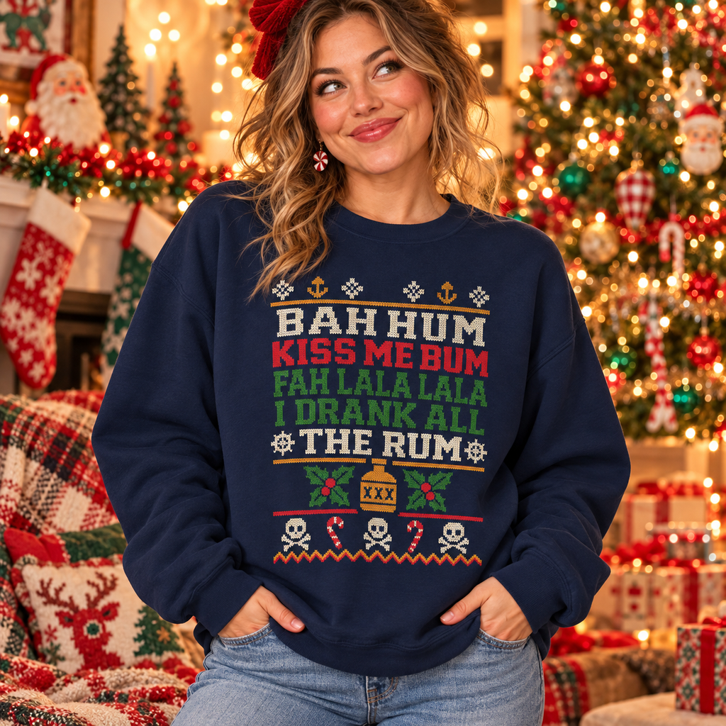 Woman in a navy Bah Hum Kiss Me Bum pirate ugly Christmas sweater sweatshirt in front of a decorated Christmas tree