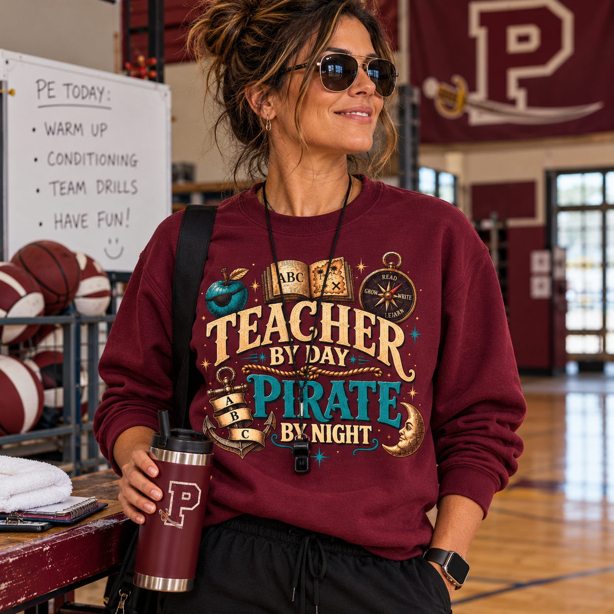 Coach in sunglasses in a school gym holding a tumbler, wearing a maroon Teacher by Day Pirate by Night sweatshirt