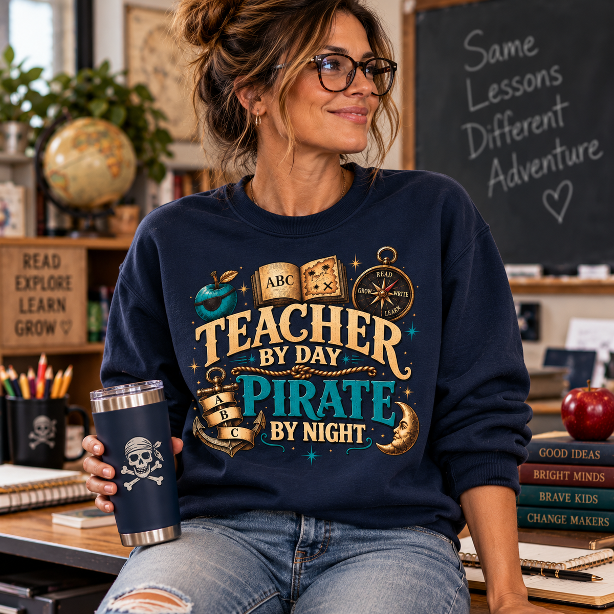 Teacher sitting at a classroom desk by a chalkboard, wearing a navy Teacher by Day Pirate by Night sweatshirt