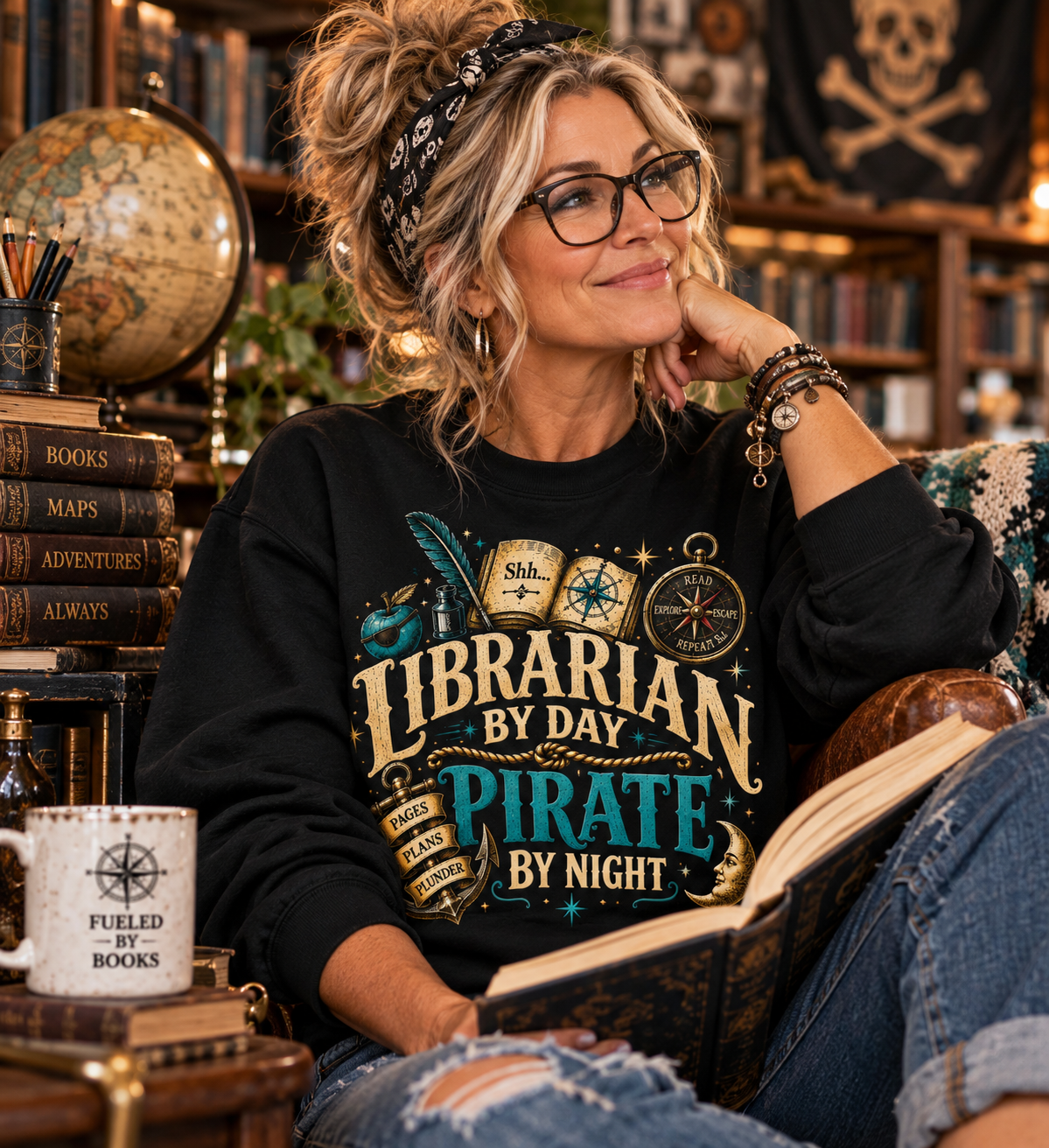 Woman in a black Librarian by Day Pirate by Night sweatshirt reading in a library armchair