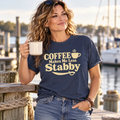 Woman holding a coffee mug on a marina dock, wearing a navy Coffee Makes Me Less Stabby Comfort Colors t-shirt