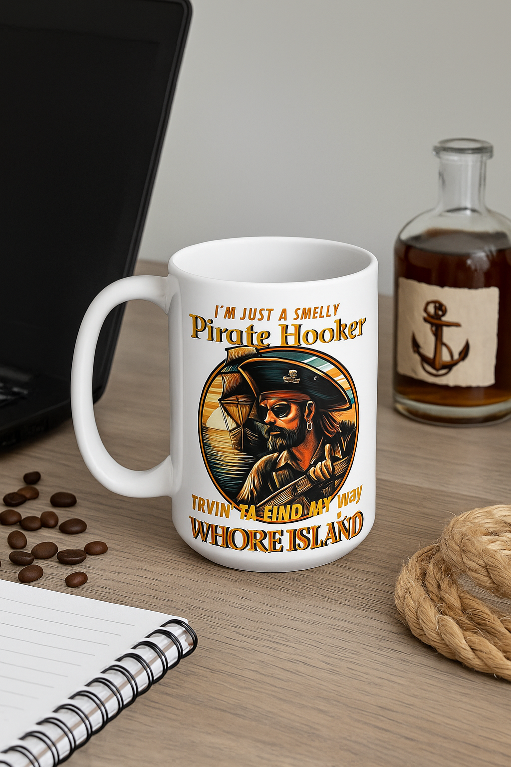 Smelly Pirate Hooker mug on a desk beside a laptop, a notebook and a small bottle