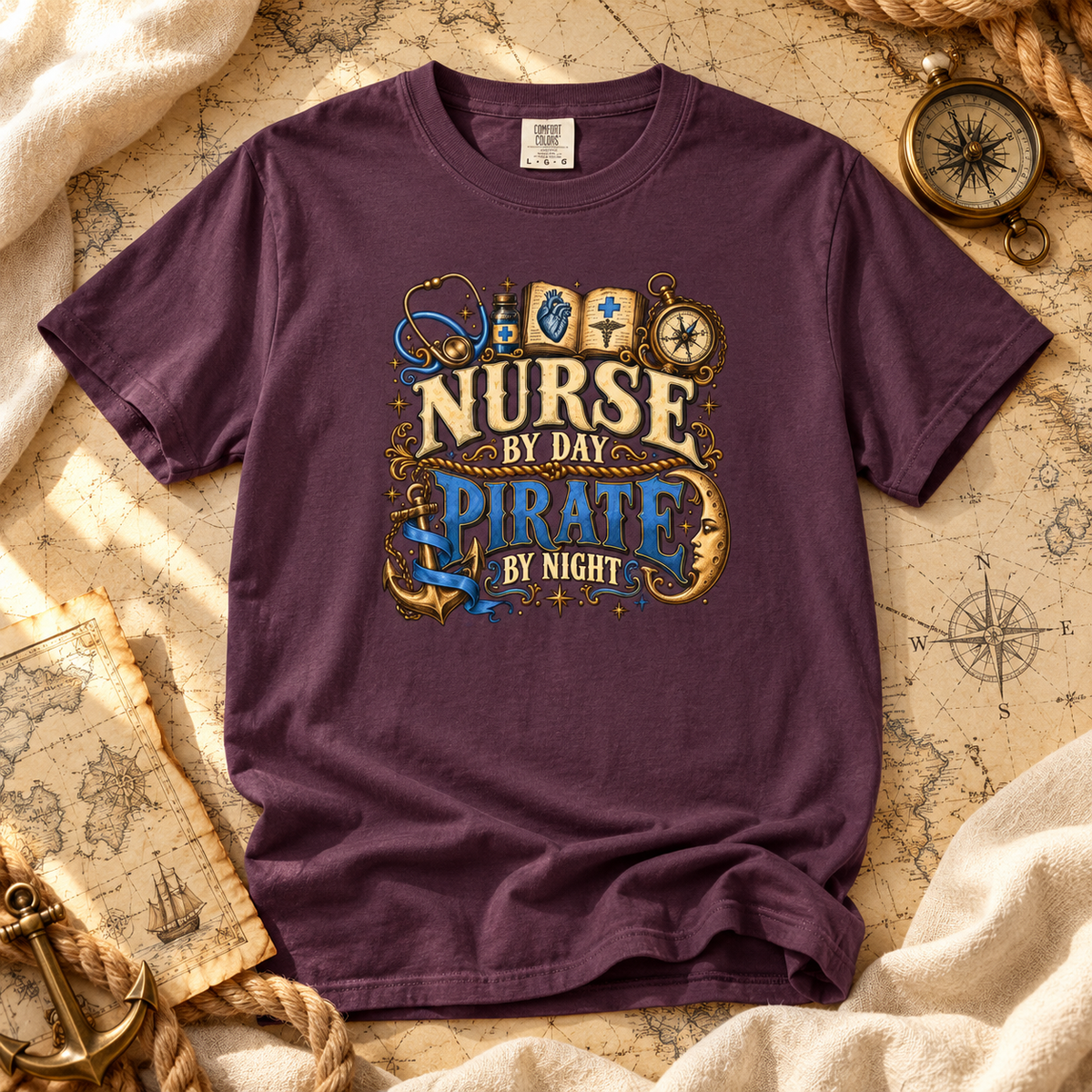Wine colored Nurse by Day Pirate by Night tee laid flat on an old sea chart with a compass and anchor