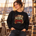 Woman on a ship dock at sunset wearing a black Nurse by Day Pirate by Night sweatshirt with red PIRATE lettering
