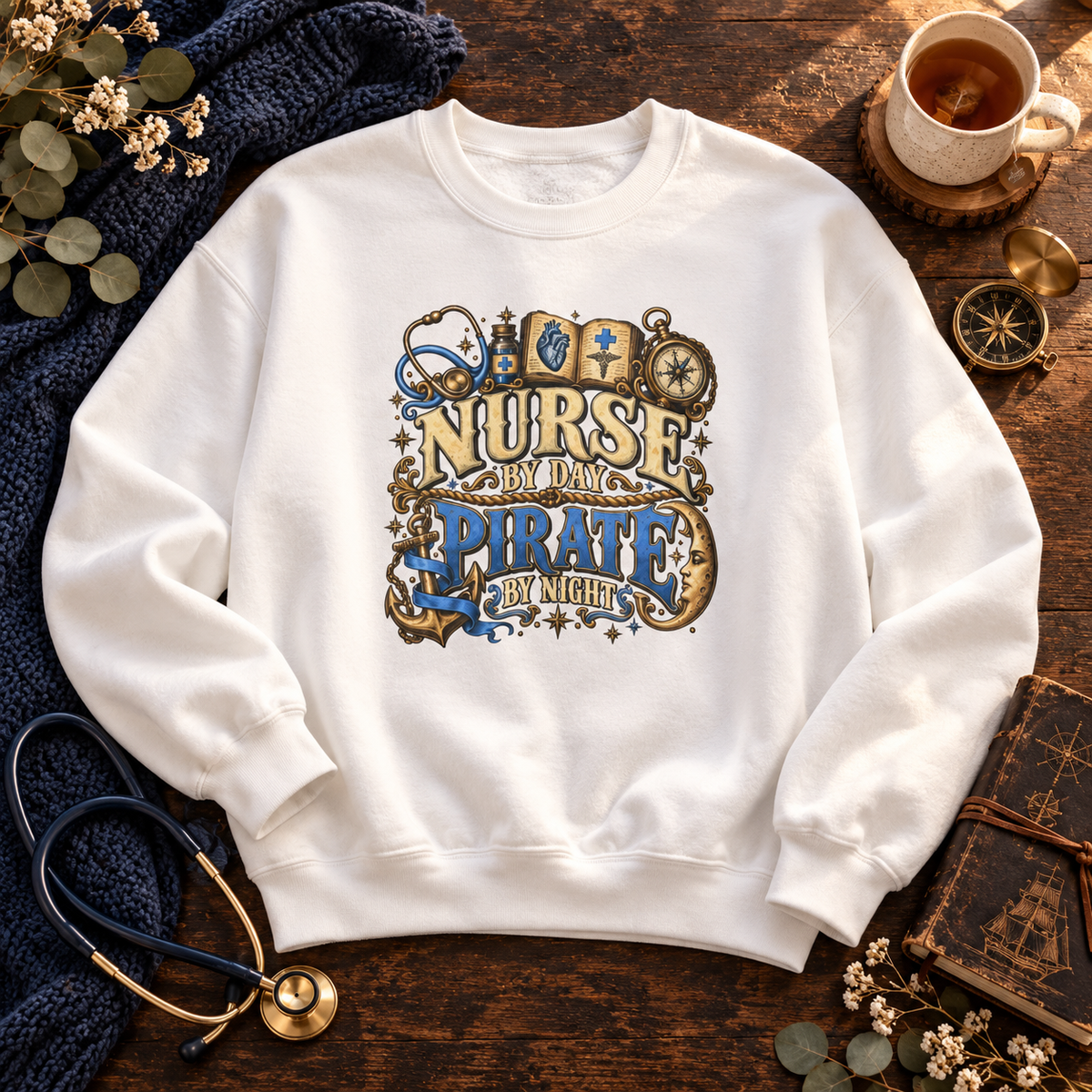 White Nurse by Day Pirate by Night crewneck in ceil blue and gold on a wood table with a stethoscope